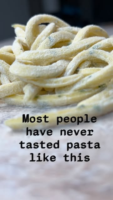 Close-up of fresh handmade tagliatelle pasta with herbs on a floured board